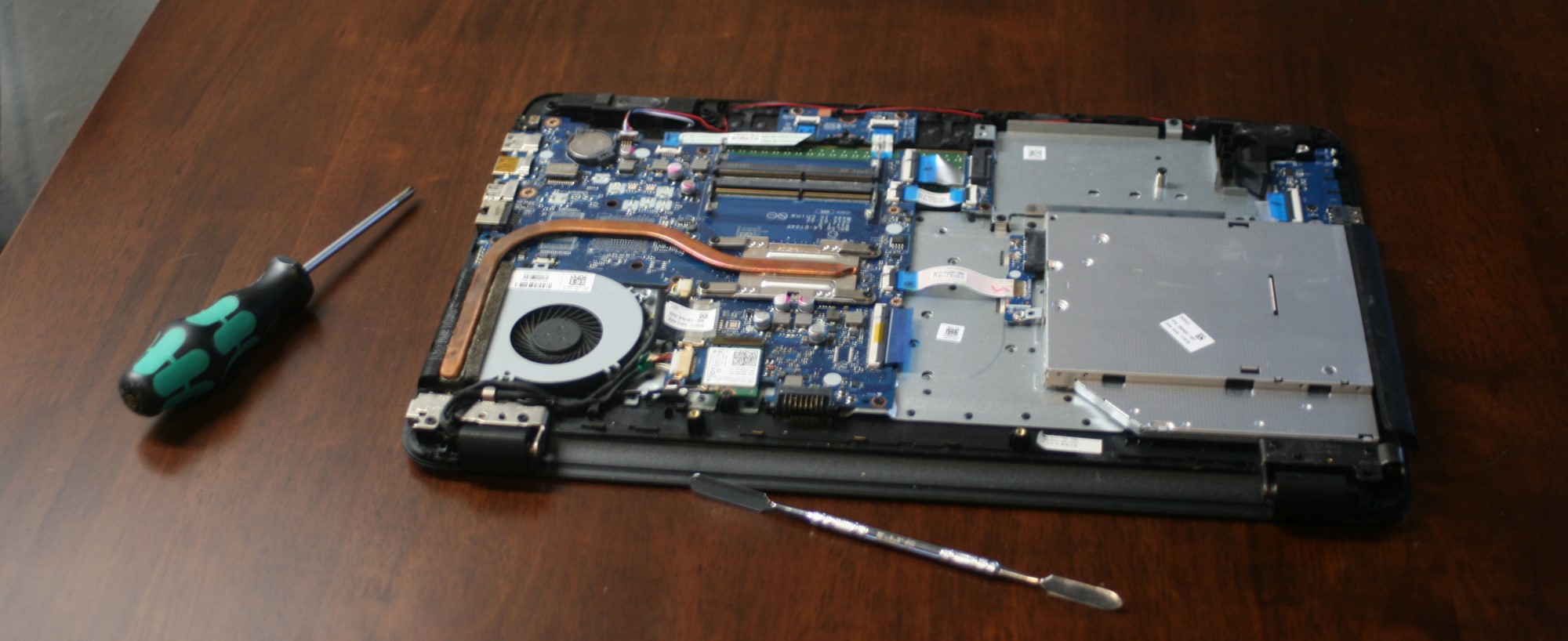 Laptop with back cover off and screwdriver on the table