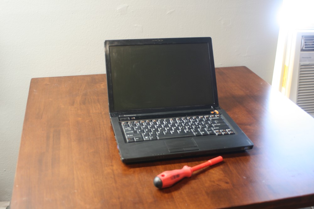 Laptop and screwdriver on wooden table